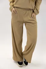 Pantalón tostado de tejido acanalado, de corte amplio y recto, con cintura elástica y bolsillos laterales.