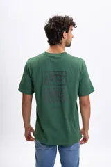 Remera de manga corta color verde jaspeado con un estampado gráfico en la espalda que simula dos casetes de audio apilados.