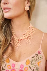 Collar color salmón oscuro, confeccionado a base de pequeños abalorios y cuentas formando flecos colgantes entrelazados.