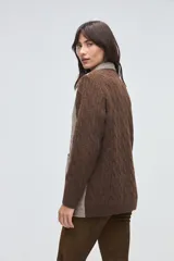 Trench de lana fina sin teñir, con diseño de textura combinada. Presenta mangas y espalda tejidas con patrón de trenzas, cuerpo liso, cuello camisero, cierre frontal con botones y bolsillos delanteros funcionales.