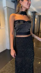 Falda larga negra de tejido red calada con lurex dorado, pretina elástica y tajos laterales. Incluye forro en la zona del caderín.