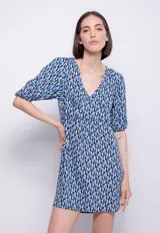 Vestido corto con estampado geométrico en tonos azul, blanco y negro. Tiene escote en V, mangas abullonadas y corte en la cintura.