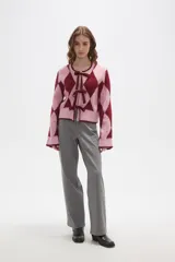 Cardigan de punto con diseño de rombos en tonos rosa y bordó. Presenta cierre frontal mediante lazos anudados, cuello redondo y mangas largas con puños acanalados.