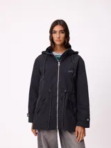 Rompevientos negro con capucha ajustable mediante cordones, cierre frontal de cremallera y ajuste en la cintura con cordón. Presenta logo de la marca bordado en el pecho y puños con detalle de botón.