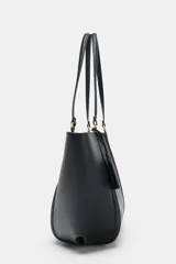 Bolso tipo shopper de hombro en color beige, con diseño estructurado, doble asa y detalle de pespuntes verticales en el cuerpo. Incluye un colgante decorativo tipo etiqueta y cierre imantado.