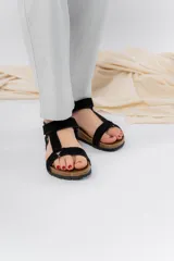 Sandalias negras con tiras de cuero sintético, base anatómica de corcho y suela antideslizante.