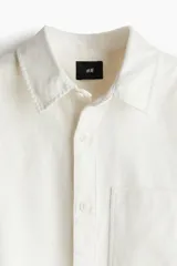 Sobrecamisa color crema de sarga de algodón, corte regular, con cuello inglés, tapeta clásica, bolsillo de parche en el pecho, mangas largas con puños abotonados y bajo recto.