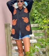 Cárdigan negro de lana merino con bordados de flores color naranja.