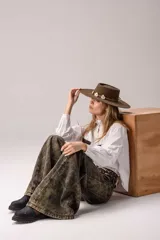 Camisa blanca de corte clásico con cuello alto tipo victoriano con detalle de puntilla. Presenta bolsillos frontales aplicados con textura de cuero con pelo en estampado animal print vacuno. Posee cierre frontal con botones y mangas largas con puños estructurados.