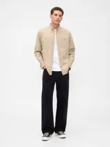 Camisa de corte clásico confeccionada en tejido Oxford, color verde oliva. Presenta cuello abotonado, cierre frontal con botones, mangas largas con puños abotonados y un bolsillo en el pecho con el logo del oso Brannan bordado.