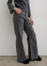 Pantalón de jean negro de corte recto y tiro medio, con cierre frontal de botón y cremallera, y bolsillos laterales y traseros.
