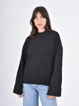 Buzo de tejido de punto color negro, con cuello redondo, mangas largas con puños anchos y ruedo acanalado.