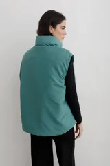 Chaleco puffer con cuello alto y cierre frontal oculto, estampado con diseño floral y de aves en tonos rojos sobre base azul oscuro.