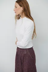 Polera de manga larga con cuello alto y detalle de volados en el borde. Confeccionada en tejido acanalado de textura suave y ajuste al cuerpo.