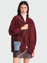 Funda para teléfono tipo crossbody de cuero granulado en color azul, con solapa frontal, cierre de botón a presión dorado y correa larga ajustable.
