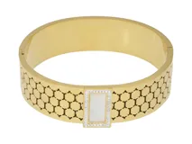 Esclava rígida de acero con baño de oro, con diseño de malla hexagonal calada. Presenta un aplique central rectangular con incrustaciones de circonias y centro de nácar.