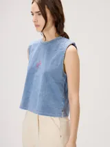Musculosa crop de algodón con efecto acid wash en color lila, cuello redondo, hombreras marcadas y pequeño bordado central en el pecho.
