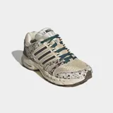 Championes Adidas Adistar Control 5 de estilo running retro, con exterior de malla transpirable en tono beige y detalles con estampado animal print tipo dálmata o vaca en tonos marrones y blancos. Cuenta con las clásicas tres tiras laterales en marrón oscuro, cordones verdes y suela amortiguada.