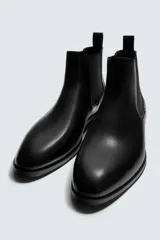 Bota estilo chelsea de cuero color marrón, con paneles elásticos laterales, tirador trasero y horma en punta con suela de tacón bajo.