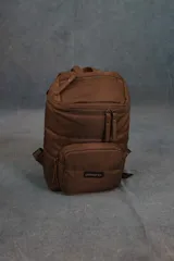 Mochila matera de diseño vertical, color gris azulado, con acabado acolchado y cierres frontales. Cuenta con un compartimento principal espacioso, un bolsillo frontal externo y un asa superior para transporte manual.