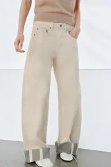 Jeans de tiro medio color beige, corte relaxed leg y largo al tobillo. Cuentan con cinco bolsillos y bajo con vuelta a contraste en gris. Cierre frontal con cremallera y botón.