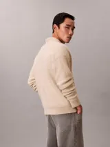 Sweater de punto de lana de alpaca cepillada, color beige, con cuello johnny y manga larga. Diseño de corte regular con puños y ruedo acanalados.
