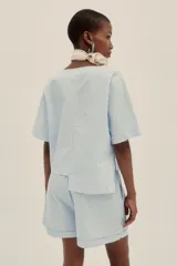 Conjunto celeste a rayas verticales, compuesto por un top corto de mangas cortas y un short de tiro alto con pinzas.