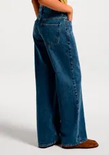 Pantalón de jean azul oscuro, tiro medio, corte wide leg (pierna ancha y recta).
