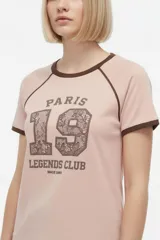 Remera de algodón blanca de manga corta estilo ringer, con cuello y puños en contraste negro. Presenta un estampado frontal con el número '28' relleno de encaje y la inscripción 'San Francisco Sports Club'.
