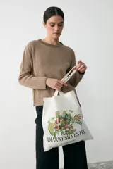 Tote bag de tela color crudo con estampado botánico de ilustraciones históricas y la inscripción Diario Silvestre. Cuenta con dos asas superiores para llevar al hombro.