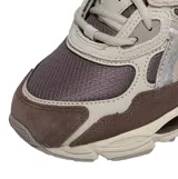 Championes Asics modelo Gel-Nyc, en combinación de tonos marrón, gris y detalles plateados. Presentan diseño técnico con malla transpirable, refuerzos sintéticos y suela amortiguada.