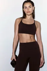 Top deportivo SculptMove color marrón, con escote redondo, breteles finos cruzados en la espalda y bajo elástico. Cuenta con copas forradas con relleno extraíble.