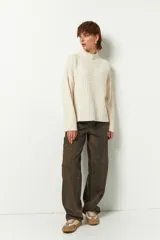 Polera gris de tejido tramado, cuello alto y mangas holgadas.