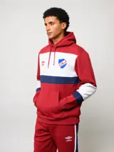 Canguro con capucha de Umbro del Club Nacional de Football, con diseño de bloques de color en azul, blanco y rojo. Presenta bolsillo frontal tipo canguro, cordones ajustables en la capucha y logos bordados del club y la marca.
