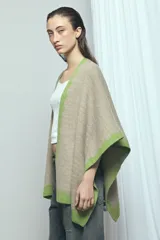Poncho marrón con detalles de bordes ondulados en color rosado, confeccionado en mezcla de acrílico, poliéster y elastano, de diseño abierto y mangas amplias.
