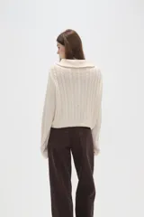 Saco de punto de algodón con diseño de trenzas, cuello alto y cierre frontal completo. Presenta un corte al cuerpo y mangas largas.
