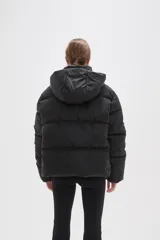 Campera puffer color beige con diseño capitoneado, capucha integrada y cierre frontal oculto. Presenta bolsillos laterales y un corte holgado.