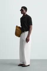 Polo negro de manga corta con cuello solapa y abertura frontal. Presenta un tejido jacquard con textura geométrica sutil.