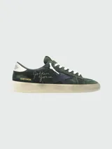 Zapatillas Golden Goose modelo Stardan, confeccionadas en gamuza color verde oscuro con detalles en cuero nappa. Presentan la icónica estrella lateral en azul marino, firma de la marca bordada en el lateral y suela con efecto desgastado.