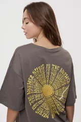 Remera de manga corta y cuello redondo, de corte oversized en color marrón, con texto bordado o estampado a lo largo del escote en el hombro izquierdo.