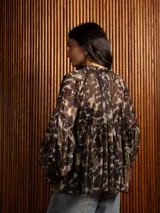 Blusa de gasa con estampado abstracto en tonos oscuros, cuello redondo con lazo ajustable, corte holgado con frunces y mangas largas abullonadas con puños elásticos.