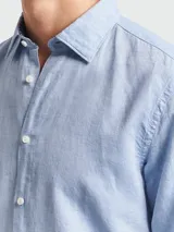 Camisa de manga larga para hombre, color celeste claro, con cuello clásico y botones frontales. El interior del puño presenta un estampado geométrico en contraste en color negro y blanco.