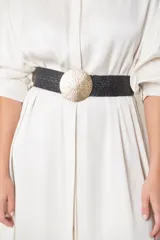 Cinturón plateado elástico con hebilla redonda metálica plateada.