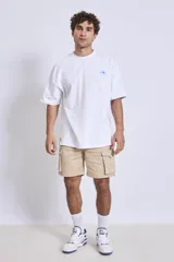 Remera de algodón color verde oliva, corte oversize, con cuello redondo y un pequeño logo bordado en el pecho.