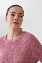 Sweater de punto fino en color verde, con cuello redondo y mangas largas. Presenta un detalle integrado de pañuelo estampado con motivos florales en la parte inferior, que se cruza sobre la cintura.