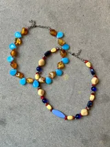 Collar doble de abalorios multicolor con cuentas de acrílico en tonos beige, azul, rojo y celeste, intercaladas con piedras y cristales. Cuenta con cadena y cierre de acero.