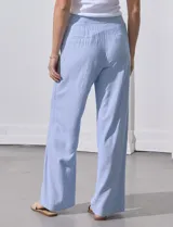 Pantalón de lino estampado a rayas verticales celestes y blancas, marca Zac & Rachel. Tiene pretina con botones, cierre y broche metálico, bolsillos delanteros y bolsillos traseros simulados.