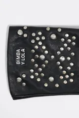 Guantes de cuero negro con aplicación de tachas metálicas plateadas en el dorso y logo de la marca estampado en la muñeca.