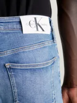 Jeans de hombre, corte skinny, talle bajo, con lavado azul medio vintage y efecto ligeramente desgastado. Confeccionados con algodón reciclado.