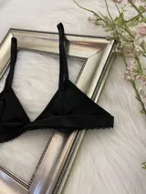 Bralette negro de lycra con corte triangular, breteles regulables y cierre trasero con gancho.